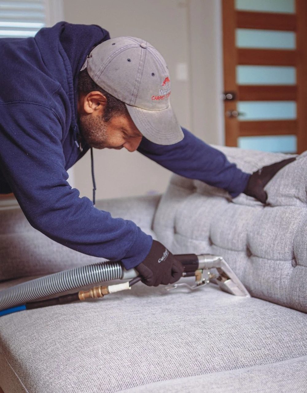 Terence's team cleaning a couch on a Waratah Carpet Cleaning job